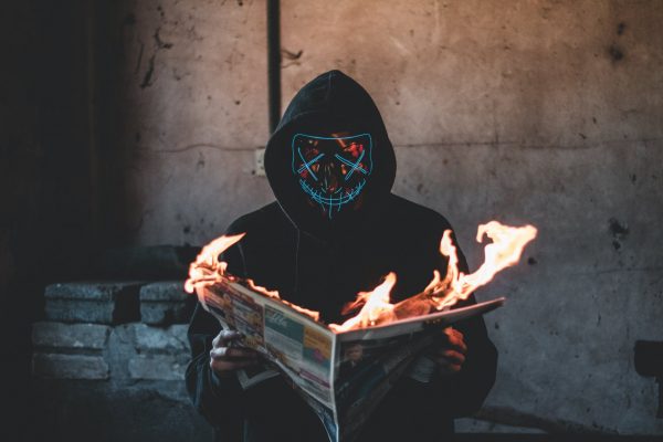 person holding a burning news paper close up photography